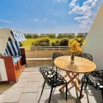 Südterrasse mit Strandkorb sowie Tisch mit vier Stühlen